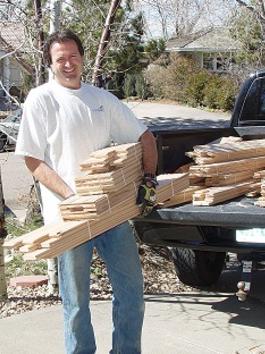 A man holding wood in front of a truck.