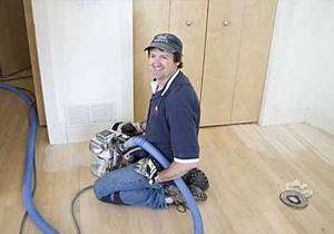 A man sitting on the floor holding a vacuum cleaner.