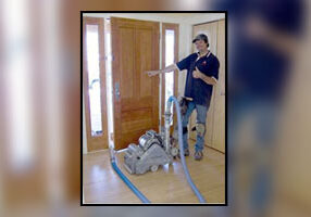 A man standing in front of a door with a hose attached to it.