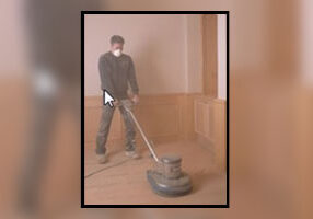 A man is using a vacuum to clean the floor.